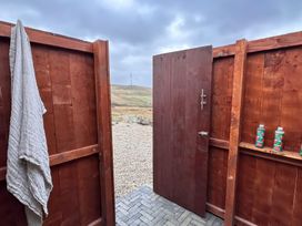 An outdoor shower area with a door open revealing bottles and a towel at Cobble Stone Cottage near Leabgarrow, County Donegal