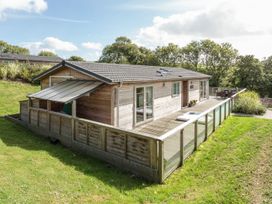 A lodge with decking and glass railing in the garden at 2 Tree Tops in Lanreath