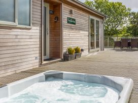 An outdoor area with a hot tub and seating at Two Tree Tops in Lanreath