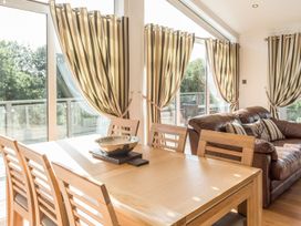 A dining room with a table and chairs, and a couch at 2 Tree Tops in Lanreath