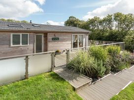 A wooden cabin with decking and plants at 2 Tree Tops in Lanreath