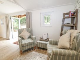 A snug with armchairs and a bookshelf at Charltons Hollow Cabin Haywards Heath
