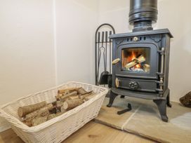 A living room with a wood stove and firewood at Charltons Hollow Cabin in Haywards Heath