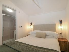 A bedroom with a bed and a bathroom door at Charltons Hollow Cabin Haywards Heath