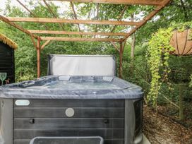 A hot tub under a wooden structure in an outdoor area at Charltons Hollow Cabin in Haywards Heath