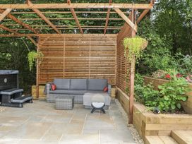 An outdoor seating area with a sofa and hot tub at Charltons Hollow Cabin in Haywards Heath