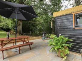 An outdoor seating area with a table and umbrella at Charltons Hollow Cabin in Haywards Heath