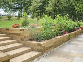 Garden with wooden steps and flower beds at Charltons Hollow Cabin in Haywards Heath