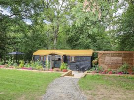 An outdoor area with a cabin and chairs at Charltons Hollow Cabin in Haywards Heath