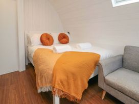 A bedroom with a bed and cushions at Bumblebee Glamping Pod in Malton