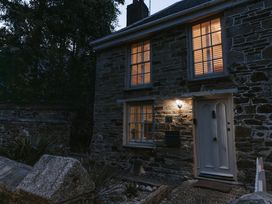 A stone house with lit windows and a door at Tamarisk Cottage in St. Agnes