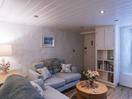 A living room with a couch, coffee table, and bookshelf at Tamarisk Cottage in St. Agnes