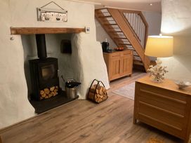 A living room featuring a wood stove and wooden cabinet at Tamarisk Cottage St Agnes