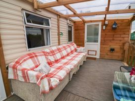 A conservatory with a couch and table at Big Bertha by the Sea in Northam