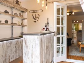 A kitchen with a bar and shelves at Honeysuckle Cottage in Swaffham