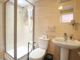 A bathroom with a shower, toilet, sink, and mirror at Honeysuckle Cottage in Swaffham