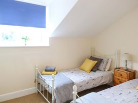 A bedroom with two beds and a lamp on a table at Honeysuckle Cottage in Swaffham