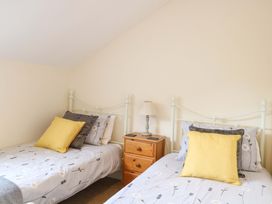 A bedroom with two beds and a lamp at Honeysuckle Cottage in Swaffham