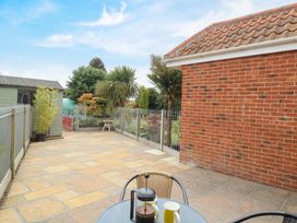 A garden with a shed and patio area at Honeysuckle Cottage in Swaffham