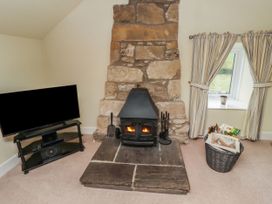 A living room with a fireplace and television at Honeymug in Branton near Powburn