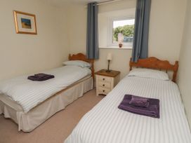 A bedroom with two single beds and a bedside table at Honeymug in Branton near Powburn