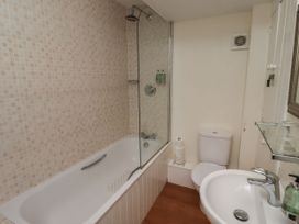 A bathroom with a bathtub, shower, toilet, and sink at Honeymug in Branton near Powburn
