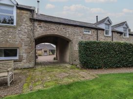 An outdoor area with a stone archway and wooden bench at Honeymug Branton near Powburn
