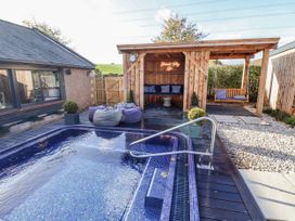 An outdoor area with a swimming pool and wooden structure at Honeymug in Branton near Powburn