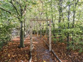 A path through trees with a wooden archway at Honeymug in Branton near Powburn