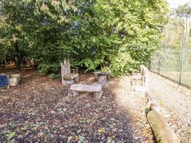 An outdoor seating area with wooden furniture and trees at Honeymug in Branton near Powburn