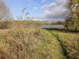 A path leading to water surrounded by bushes and trees at Honeymug in Branton near Powburn
