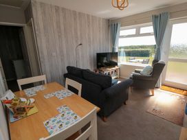 A living room with a television, sofa, and dining table at Beach House