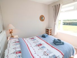 A bedroom with a bed, lamp, and storage unit at Beach House