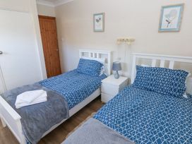 A bedroom with two beds and a bedside table at Tig Bhan in Narberth