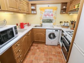A kitchen with cabinets, a washing machine, and a microwave at Static Caravan