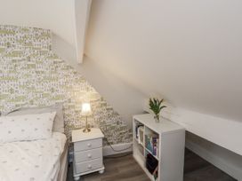 A bedroom with a bed, nightstand, lamp, and bookshelf at 1 Castle Terrace in Thirsk