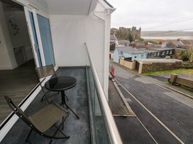 A balcony with a table and chairs overlooking a road at Cottage 1 in Laugharne