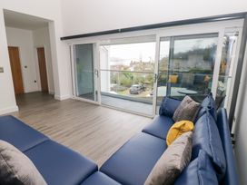 A living room with a sofa and doors to a balcony at Cottage 1 in Laugharne