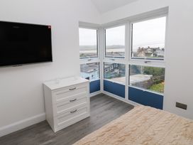 A bedroom with a television, a chest of drawers, and a bed at Cottage 1 in Laugharne
