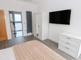 A bedroom with a bed, wardrobe, and TV at Cottage 1 in Laugharne