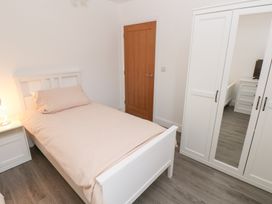 A bedroom with a bed, nightstand, lamp, and wardrobe at Cottage 1 in Laugharne