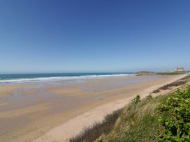 A beach with waves and people at Tradewinds in Newquay