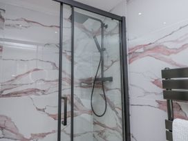 A bathroom with a glass shower and marble wall tiles at Aspen Boutique
