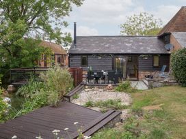 An outdoor area with a wooden deck and a table and chairs at WEST LODGE in Ashford