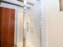 A shower enclosure with tiled walls and wooden door at WEST LODGE in Ashford