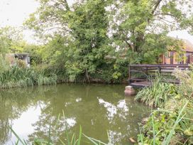 A pond with a bridge and surrounding vegetation at WEST LODGE Ashford