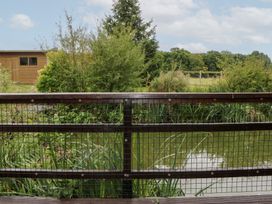 A view of a pond with plants and a wooden shed at WEST LODGE in Ashford
