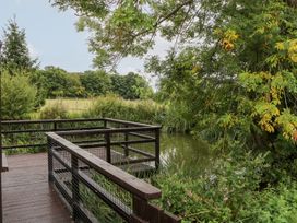 A deck by the water surrounded by trees and grass at WEST LODGE in Ashford