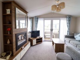 A living room with a television and a coffee table at Sea Breeze C38 Dyffryn Seaside Estate Dyffryn Ardudwy