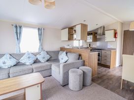 A living room with a sofa and kitchen area at Sea Breeze C38 Dyffryn Seaside Estate Dyffryn Ardudwy